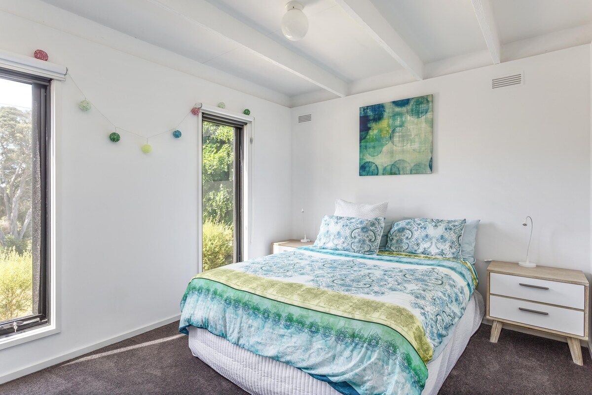 A bedroom with a bed, bedside table, and a window.