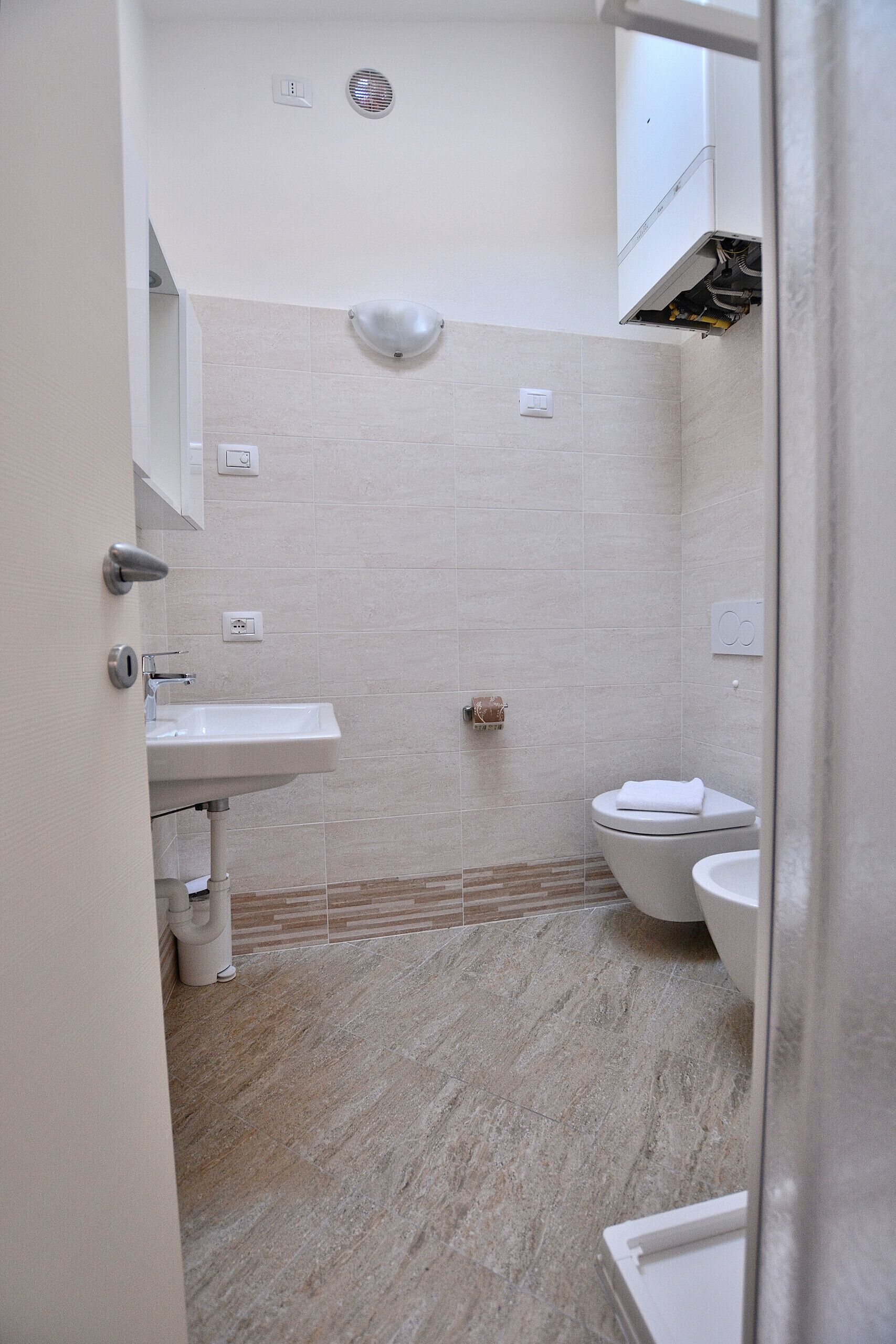 Et badeværelse med vask, toilet og bruseområde.