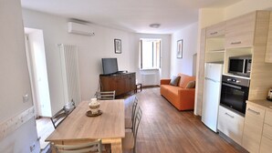 A compact living space with a dining area, kitchenette, and a sofa. - Apartment del Pescatore In Downtown (Torri del Benaco)