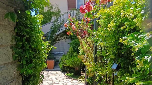 A stone pathway leading to a house with a garden.