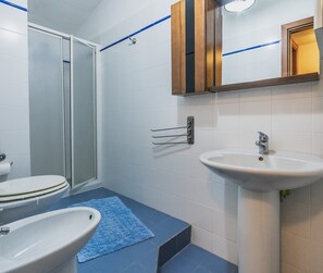 A bathroom with a toilet, sink, and shower.