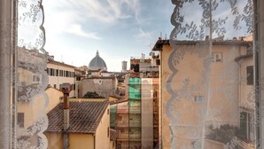A view through a window with lace curtains, featuring a cityscape with buildings, a dome structure, and a green construction site. - Great View San Marco - historic center of Florence (Firenze)