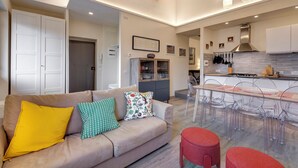 A modern living room with a sofa, clear chairs, and a kitchen area with a dining table. - Great View San Marco - historic center of Florence (Firenze)