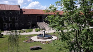 A stone building with a red-tiled roof, a circular fountain, and a stone staircase leading to an entrance. - B&B Au Chant De L'eau (Siaugues-Sainte-Marie)