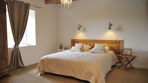 A bedroom with a large bed, wooden headboard, bedside lamps, and a window with curtains. - B&B Au Chant De L'eau (Siaugues-Sainte-Marie)