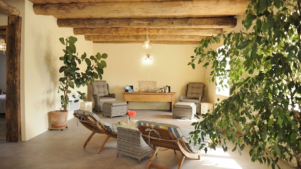 A cozy room with wicker furniture, a wooden ceiling, and a large window allowing natural light. - B&B Au Chant De L'eau (Siaugues-Sainte-Marie)