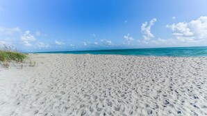 A wide sandy beach with footprints leading to the water, under a clear blue sky. - SS 81122 Expansive Ocean & Intracoastal Waterway View Condo - Vacation Rental in Ocean Village (Fort Pierce)