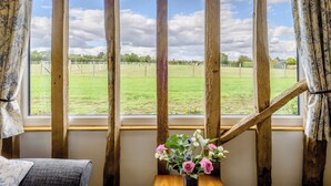 A room with a large window, wooden beams, and a view of a grassy field. - 1 bedroom accommodation in Raydon near Ipswich (Raydon near Ipswich)