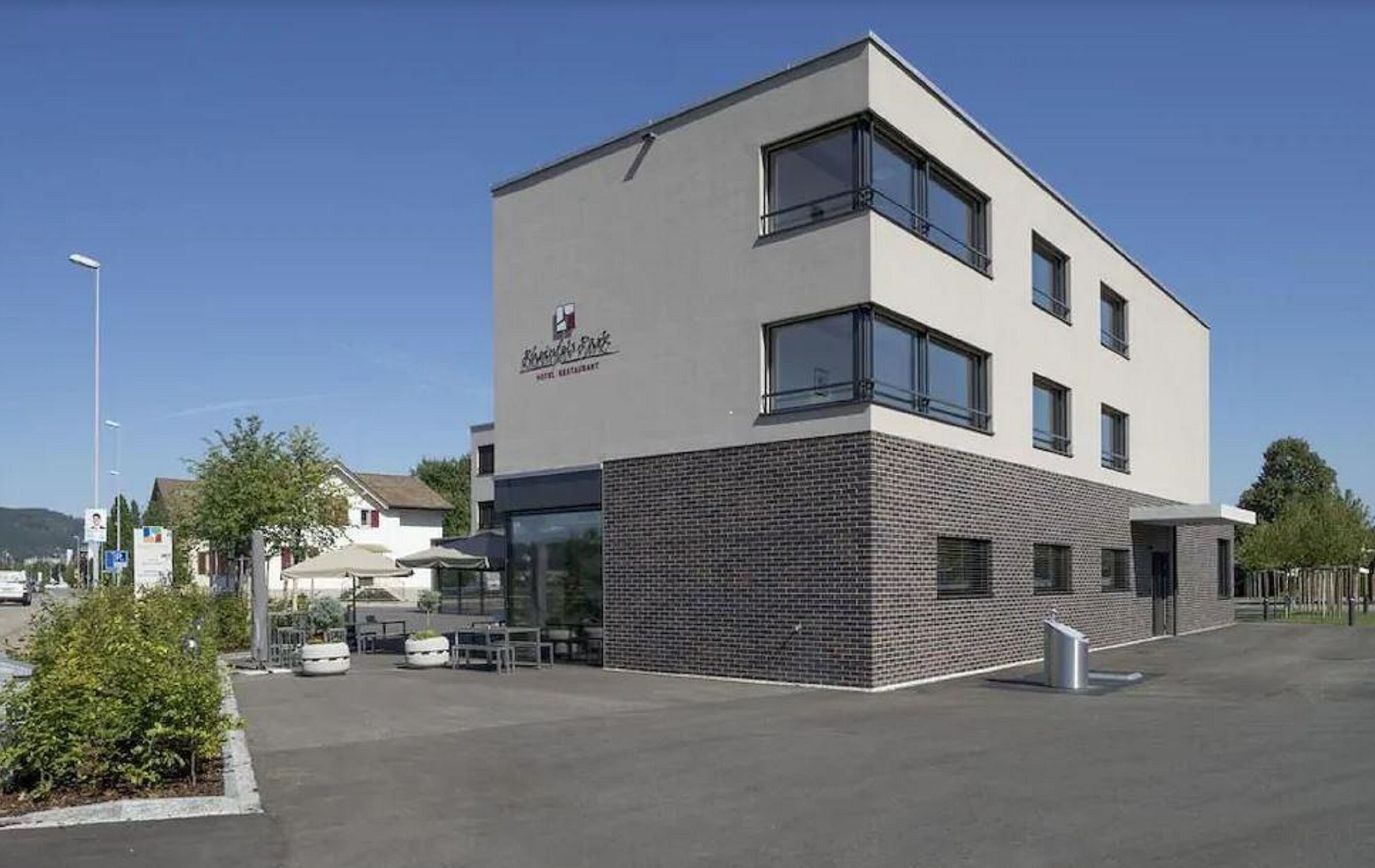 Een modern hotel met een plat dak, grote ramen en een gevel van baksteen.