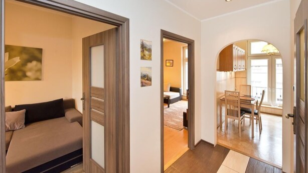 Un intérieur moderne avec un canapé, un coin repas et une cuisine visibles à travers une porte ouverte.