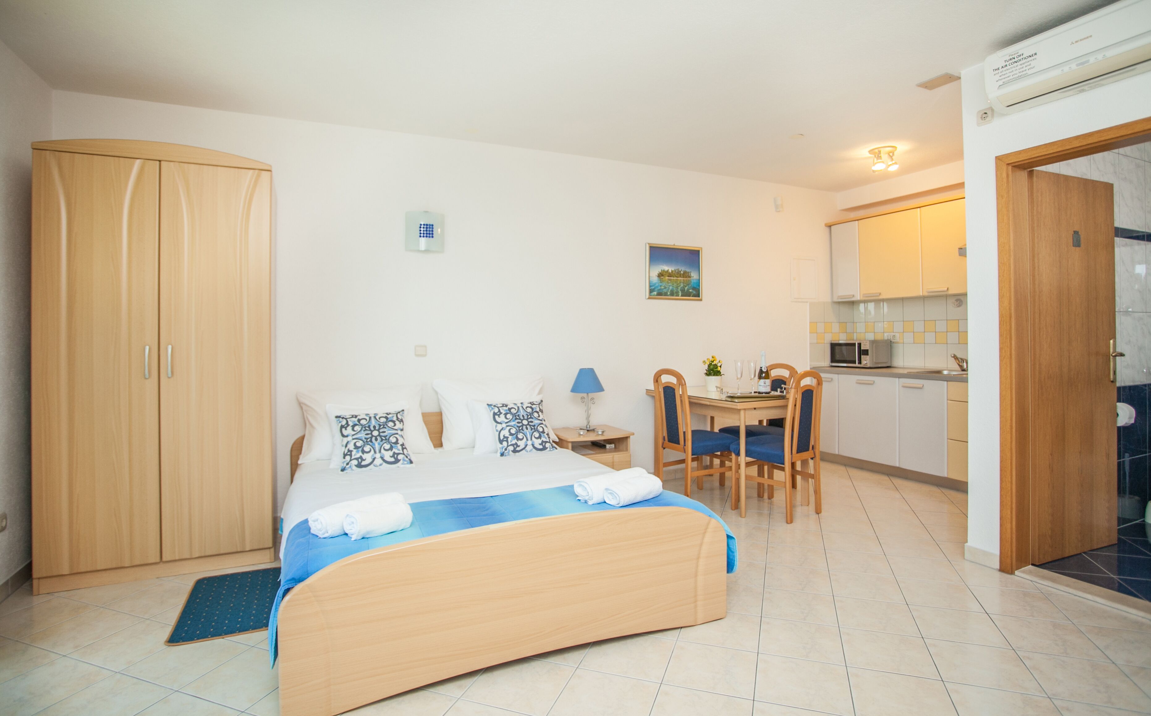 Une chambre comprenant un lit, un bureau et un coin cuisine.