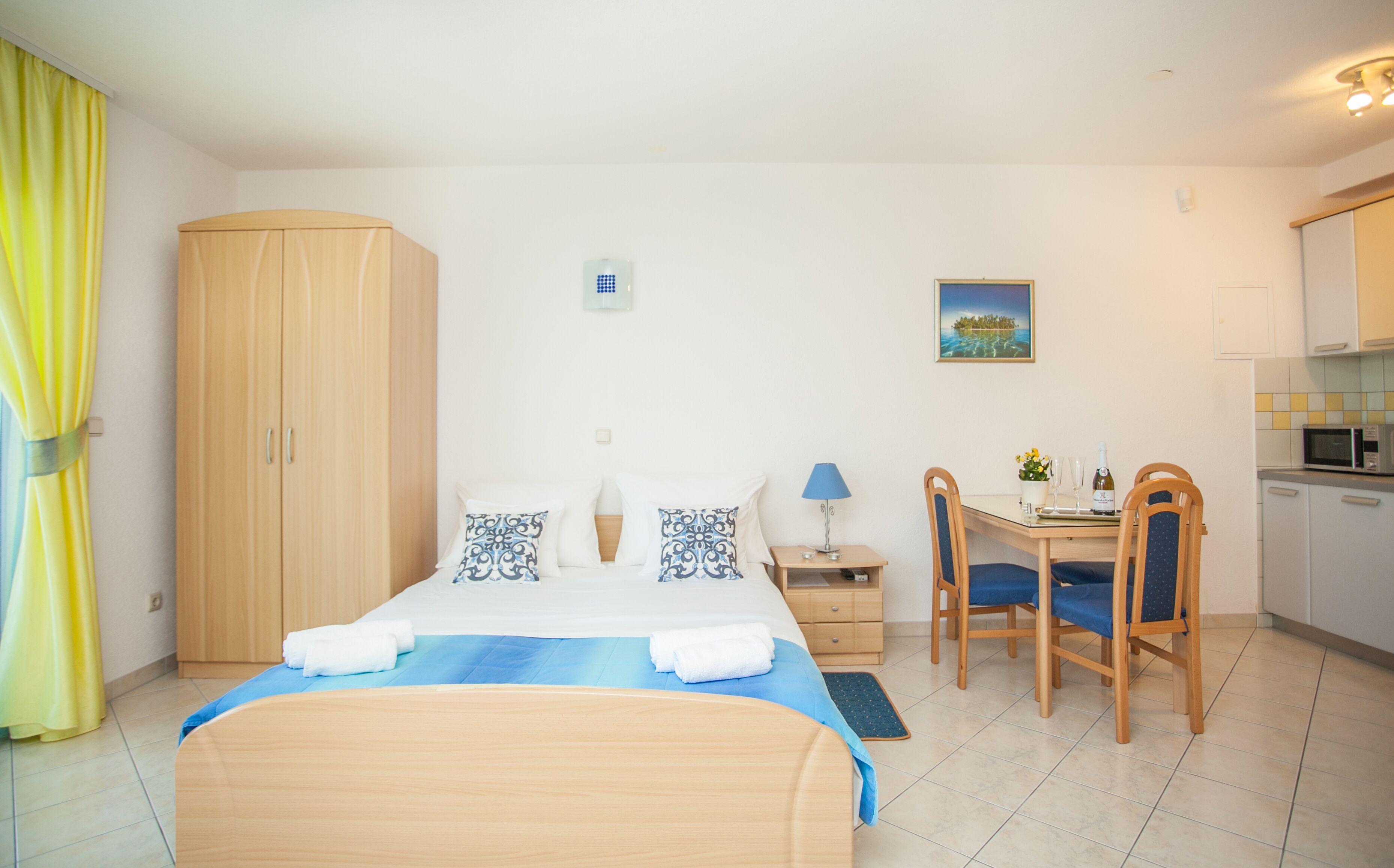 Habitación de hotel con cama, escritorio, sillas, microondas y vista al mar.