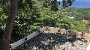 A balcony with a view of a coastal landscape, surrounded by greenery and a white railing. - Casa de la Paz (Sardinal)