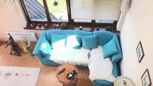 Ein Wohnzimmer mit einem blauen Sofa, einem Holztisch und einer weißen Lampe.