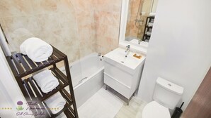 Un bagno con una vasca, un lavandino bianco, uno specchio e un porta asciugamani.