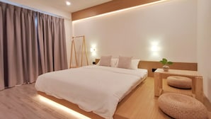 Un dormitorio moderno con una cama grande, cabecera de madera, mesitas de noche y una silla colgante.