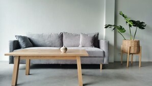 Una sala de estar moderna con un sofá gris, una mesa de centro de madera y una planta en maceta.