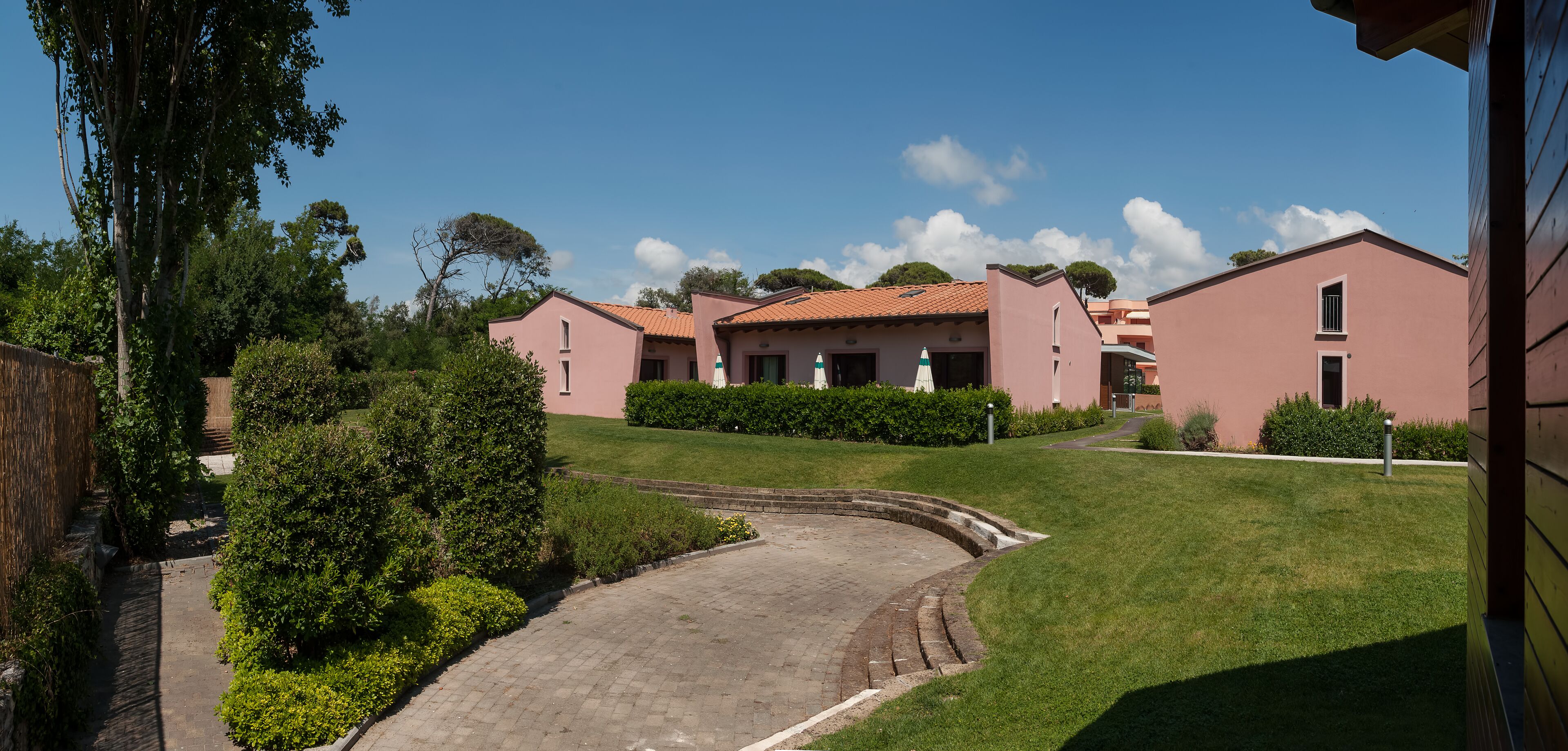 Un quartier résidentiel avec une allée pavée menant à une rangée de maisons roses aux toits en tuiles.