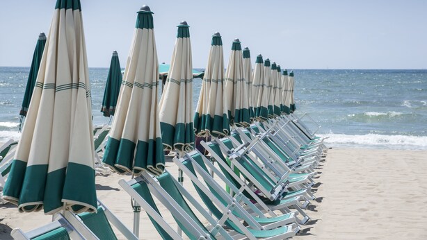 A row of beach chairs and umbrellas aligned along the shoreline. - Miramare Resort (Pisa)