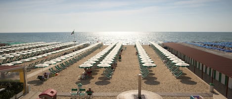 På stranden, hvit sand, solsenger og parasoller