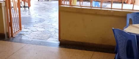 An indoor area with tiled flooring, a metal gate, and plastic chairs.