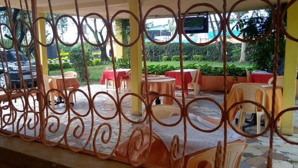 An outdoor seating area with tables and chairs, surrounded by a decorative metal fence. - Chariot County Hotel (Machakos)