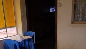 A room with a tiled floor, a table with a blue tablecloth, and blue chairs. - Chariot County Hotel (Machakos)