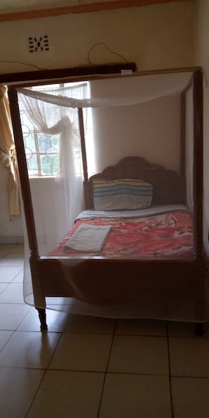 A four-poster bed with a canopy, a floral bedspread, and a pillow. - Chariot County Hotel (Machakos)