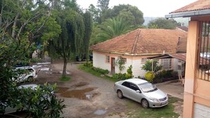 A residential area with a house featuring a tiled roof, a parked car, and a visible garage door. - Chariot County Hotel (Machakos)