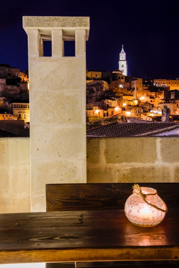 A night view of a historic town with a prominent tower and a stone wall. - L' Artiere Dimore nei Sassi (Matera)