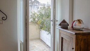 An open doorway leading to a balcony with a view of buildings and a tree. - L' Artiere Dimore nei Sassi (Matera)