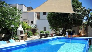 A swimming pool with a sunshade, surrounded by trees and buildings. - La Cantina - BB La Traja (Gagliano del Capo)