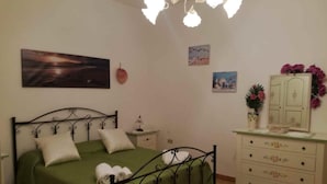 Une chambre à coucher avec un lit vert, une table de chevet, une commode et un lustre.