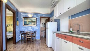 A compact kitchen with a dining area, a refrigerator, and a sink. - Terrazza 1 - BB La Traja (Gagliano del Capo)