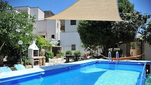 A swimming pool with a sunshade, surrounded by trees and buildings. - Terrazza 1 - BB La Traja (Gagliano del Capo)