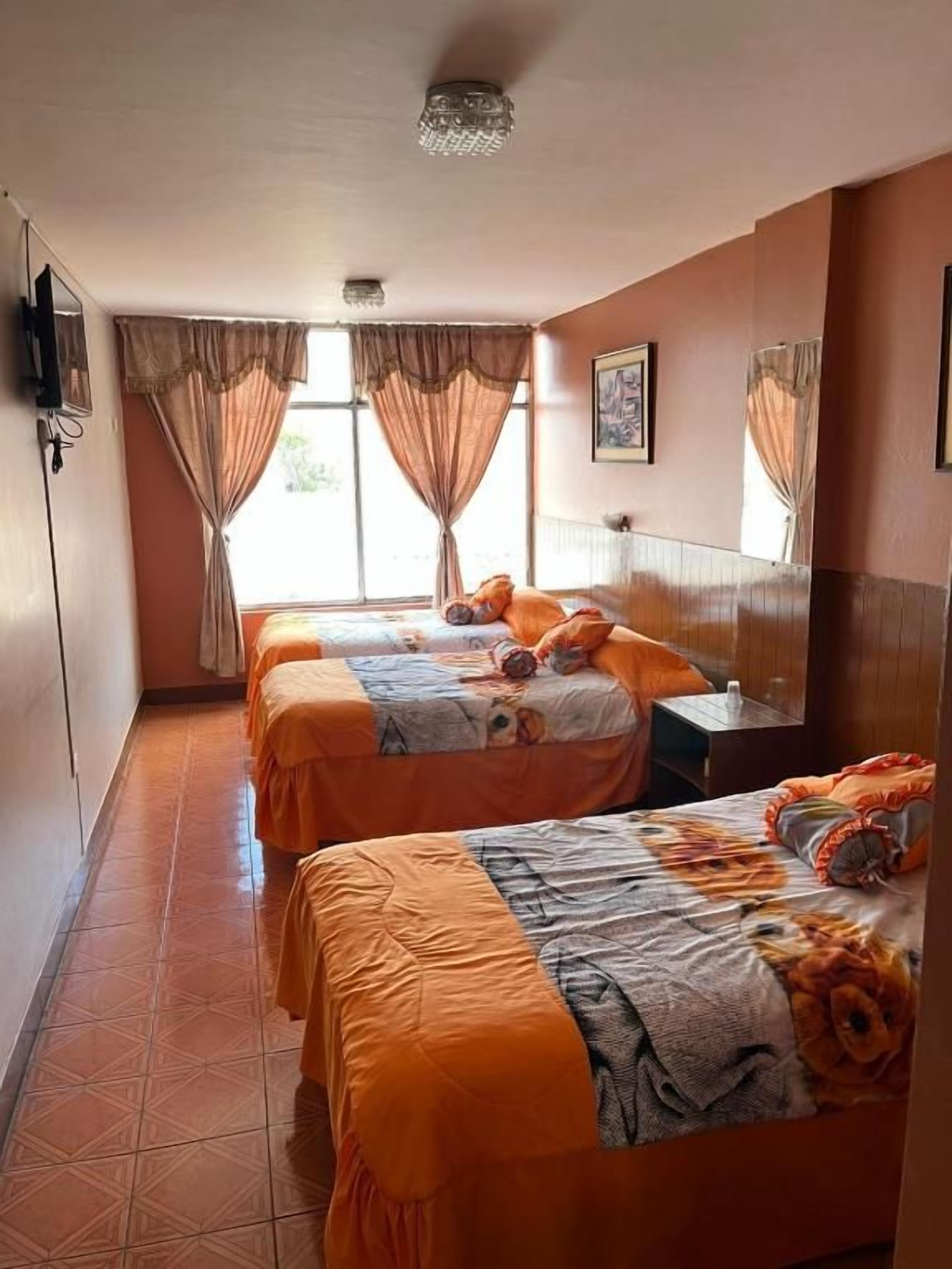 Ein Hotelzimmer mit zwei Betten, einem Schreibtisch und einem fenster mit Vorhängen.