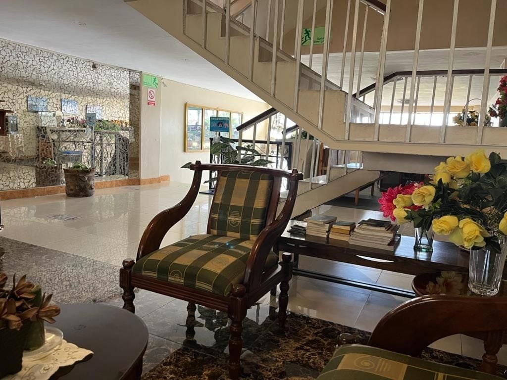A lobby with a wooden chair, a staircase, and a vase of flowers.