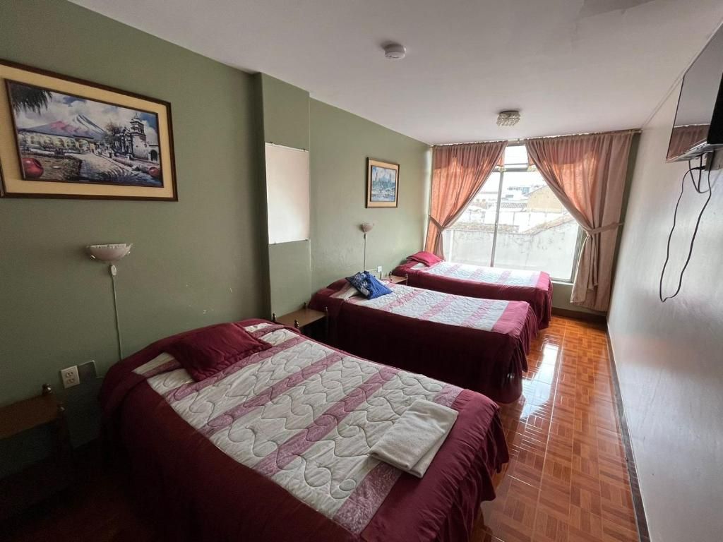 Habitación de hotel con dos camas, un cuadro en la pared y un ventanal con cortinas.