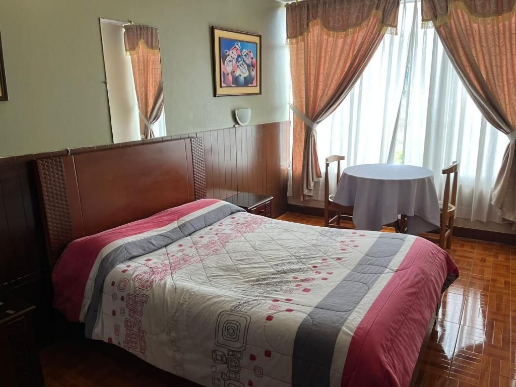 A hotel room with a bed, a round table, and a chair.