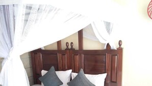 A bed with a wooden headboard, white bedding, and grey pillows. - Machakos Luxury Suites (Machakos)