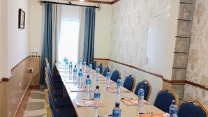 A conference room with a long table, blue chairs, and water bottles on placemats. - Machakos Luxury Suites (Machakos)