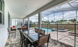 An outdoor patio with a glass table and chairs, a pool, and a view of the neighborhood. - South-Facing Pool & Spa • Princess Room • Game Room • Near Disney (Davenport)
