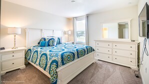 Une chambre à coucher avec un grand lit, une commode, un miroir et un téléviseur.