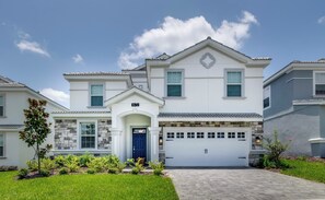 A two-story house with a garage, a stone facade, and a well-maintained lawn.