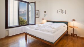 Un dormitorio con una cama de madera, una ventana con vistas a montañas y dos lámparas de noche.
