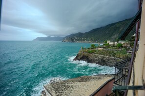 A coastal view with a rocky shoreline, a staircase leading down to the beach, and buildings on the hillside. - Il Baluardo Sea View Apartment on the Cliff (Manarola)