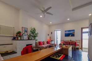 Un vaste espace de vie comprenant une cheminée, une table à manger et un ventilateur de plafond.