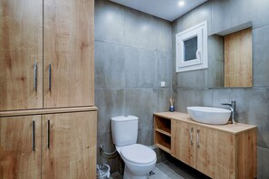 Ein modernes Badezimmer mit einem Holzkosmetikschrank, einem weißen Waschbecken und einer Toilette.
