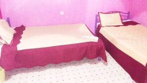 Una habitación pequeña con cama individual, pared morada y suelo blanco.