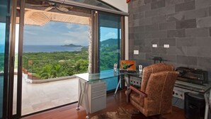 A modern office with a glass wall, a laptop, a chair, and a small desk. - Casa de los Suenos (Sardinal)